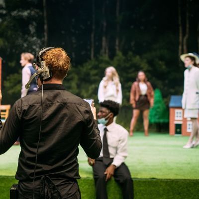 Stage Manager wearing headset and gesturing while actors are on stage
